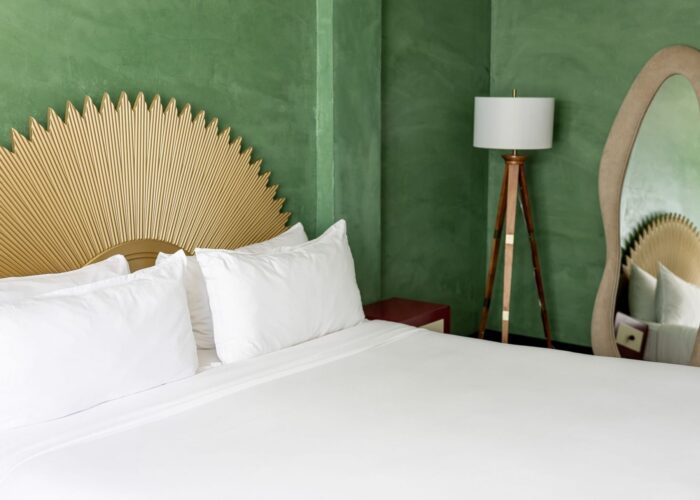 White bed with a gold sunburst headboard and wavy floor mirror in the Accessible Eclectic King Room at Crest Hotel & Sui