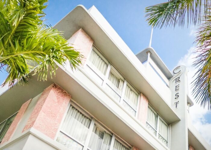Exterior of Crest Hotel & Suites framed by palm trees