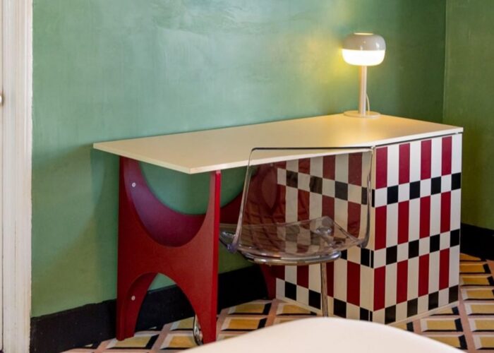 Lamp on the table with a red checkered cabinet, and a clear chair in Eclectic Double at Crest Hotel & Suites