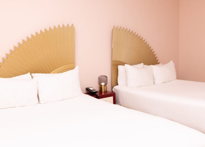 Pair of beds with gold sunburst headboards by a red nightstand and a desk lamp in Standard Double at Crest Hotel & Suite